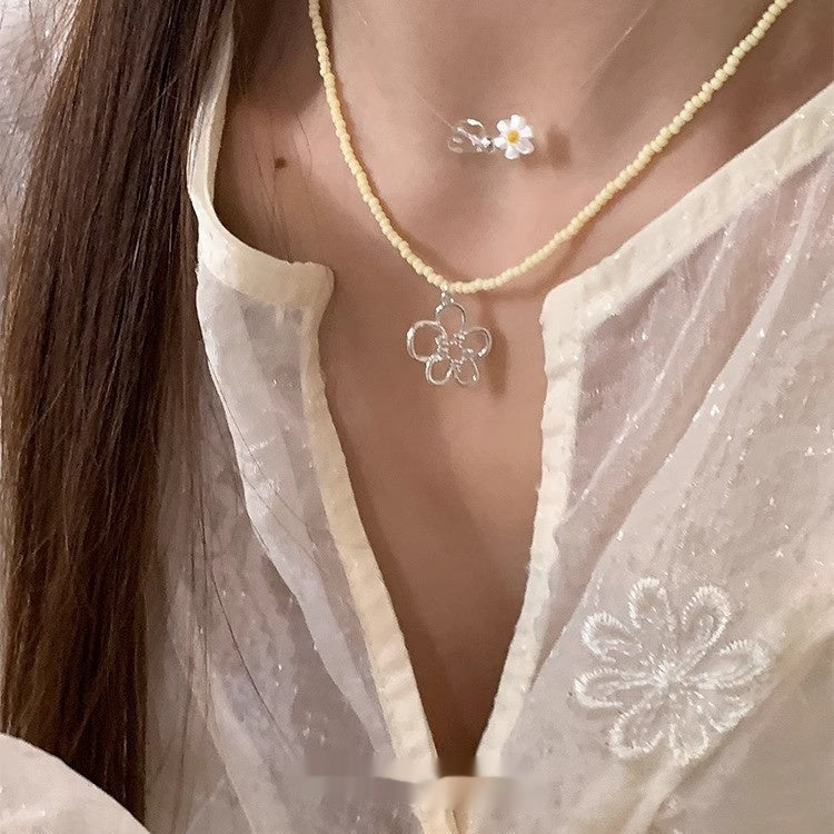 This women's necklace features a vibrant and delicate design, combining colorful yellow or blue beads with a hollow flower pendant.